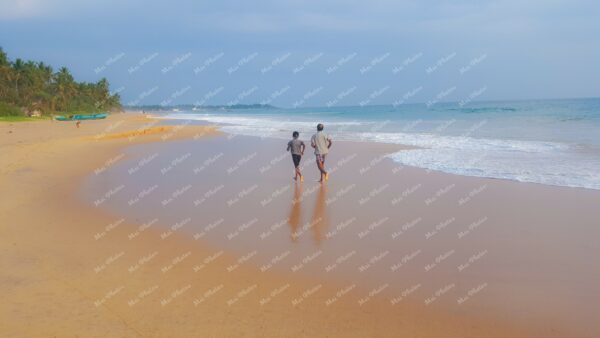 Sand, Waves, And Sea Foam With Man and Boy Running Along Beach In Hikkaduwa Sri Lanka